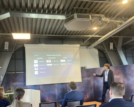 Konferenzsaal mit Publikum und Sprecher vor der Leinwand