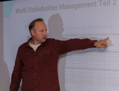 Vortragender präsentiert vor der Folie Multi Stakeholder Management